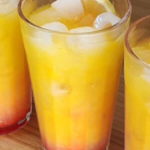 Limoncello Sunrise cocktail in a tall tumbler with ice and a slice!